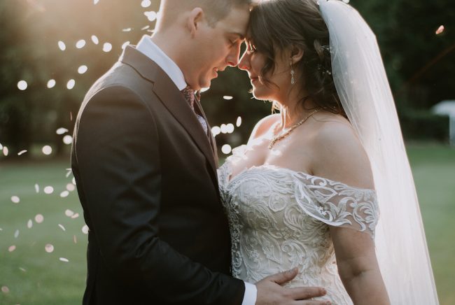 A bride and groom at The Acre rest their foreheads together in a sea of confetti